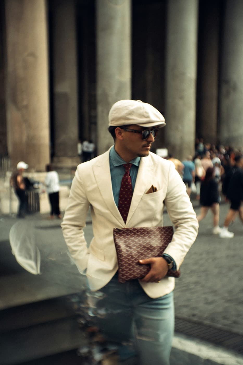 A sharply dressed professional carrying a clutch on a city street
